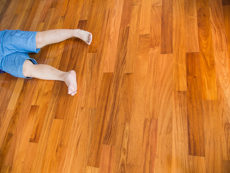 Fat Boy Wearing Blue Shorts Lying on The Wooden Parquet Floorの写真素材