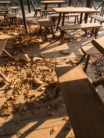The Desk and Chair on a Wooden Floor with Leaves in Abandoned Restaurantの写真素材