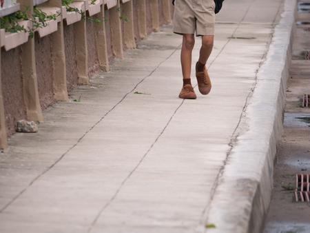 The School Boy Walking on The Footpath beside The Schoolの写真素材