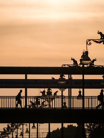 The People Crossing The Footbridge near The Statue of Elephants and Angels Light Posts behind The Sunの写真素材