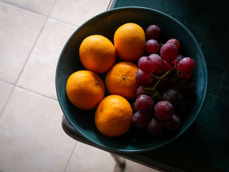 Oranges and Grapes on The Green Plate on The Deskの写真素材