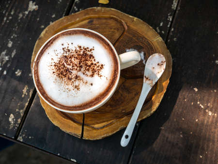 The Brown Powder of The Top of Coffee on The Woonden Plate with White Spoon in The Old Wooden Tableの写真素材