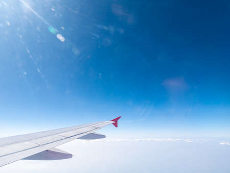 The Right Wing of The Plane has The Flare Light on The Top Left Corner behind The Bright Skyの写真素材