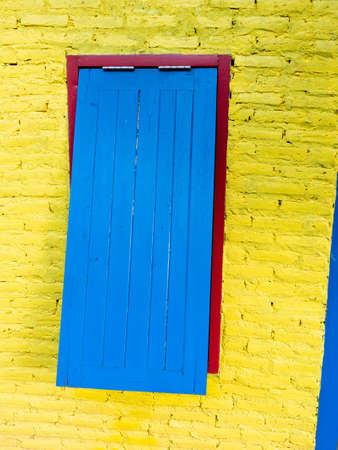 The Blue Wooden Window on The Red Frame in The Yellow Wall in The Houseの写真素材