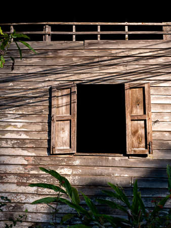 The Old Native Wooden Wall with Two Open Windows and The Shadow of The Oblique Wiresの写真素材