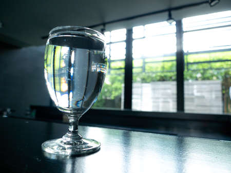 The Water in The Blur Wine Glass Reflected The Stripes on The Dark Tableの写真素材