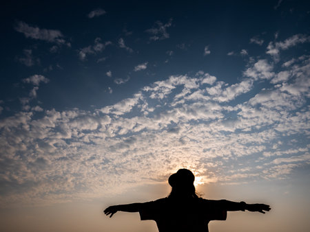 The Silhouette Woman Wearing a Hat Stands with Her Arms Crossed behind The Sun , Sky and Seaの写真素材