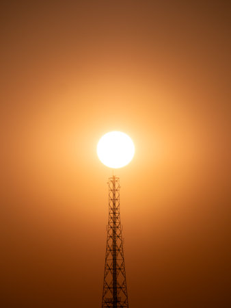 The Sun above The Silhouette Cell Site behind The Orange Backgroundの写真素材
