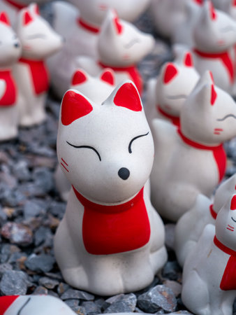 This close-up image captures a charming collection of small, white fox figurines with red ears and...