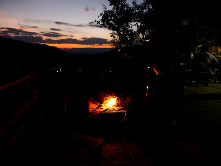 A hill tribe woman in northern Thailand warms herself by a fire in the late afternoon. The cold...