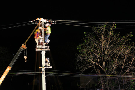 Technicians Working on Electrical Pole at Nightの写真素材