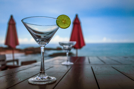 Empty glass of cocktail on the beach table by the seaの写真素材