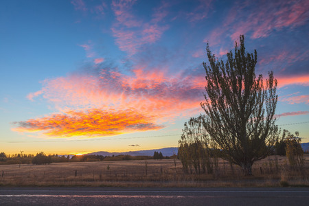 Sunrise behind grass land with clear colorful sky and nice cloudscape aboveの写真素材
