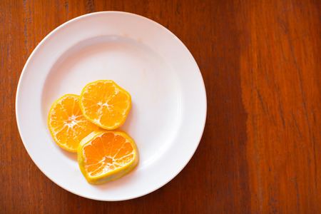 Sliced orange in white pkate on the top of wooden tableの写真素材