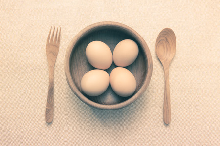 Raw Eggs in a teak bowl with teak spoon and fork ready to serveの写真素材