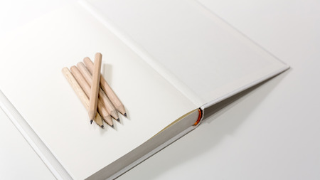 Pencils on a blank note book in black and white with selective focus and shallow depth of field.