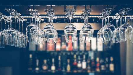 Empty glasses for wine above a bar rack in vintage tone.