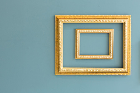 Golden classic picture frames isolated on greenish yellow wall.