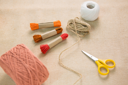 Scissors lying on fabric with many color ropes .