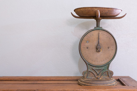 Antique scale on a wooden table against white wall.の写真素材