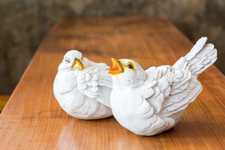Decorative white birds on top of a wooden table.の写真素材