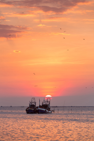 Dramatic sunset  behind the fishing boats  in the open sea, Chonburi, Thailand.の写真素材