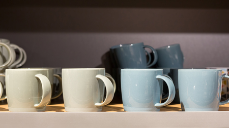 Earth tone color ceramic coffee cups in a sideboard.の写真素材