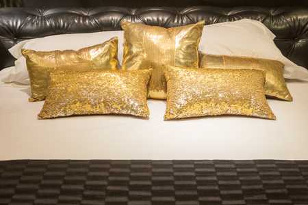 Luxury bedroom with black leather headboard and many golden pillows.の写真素材