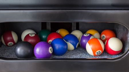 Pool balls in a inside table pocket .