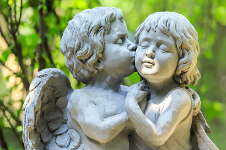 Little couple angel sculpture in green gardenの写真素材