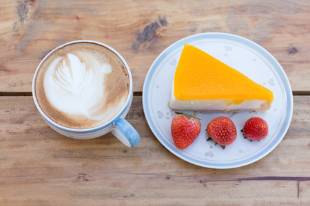 Coffee break with soft orange cake and fresh strawberries on white plate.の写真素材
