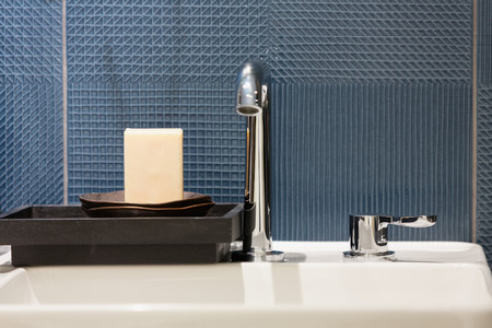 Bar of soap in a wooden tray on a white ceramic washbasinの写真素材