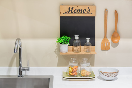 Washbasin, memo board and utensils decorated in a clean new kitchen.