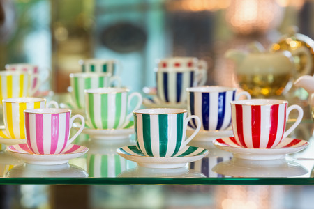 Colorful porcelain tea cups on a glass cabinet.の写真素材