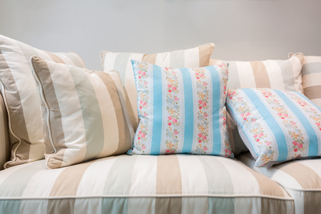 Earth tones color pillows and cushion on a contemporary style fabric sofa in a bright living room.の写真素材
