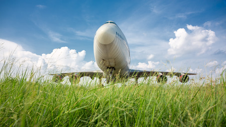 Big airplane taking off  from runway with green field and blue sky background.の写真素材