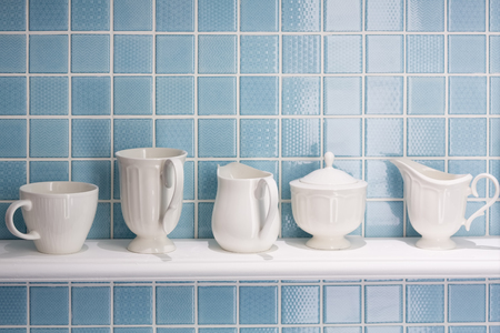 White ceramic bottle and cup on white shelf  with blue tiles wall.の写真素材