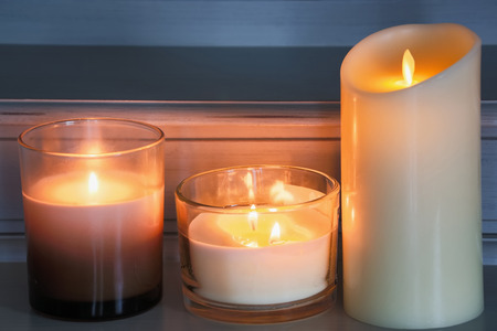Lit Scented candles on a wooden table inside a bedroomの写真素材