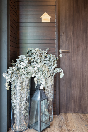 Dried flowers in  tall vases and Glass candle lamp decorated in front of wooden door.の写真素材