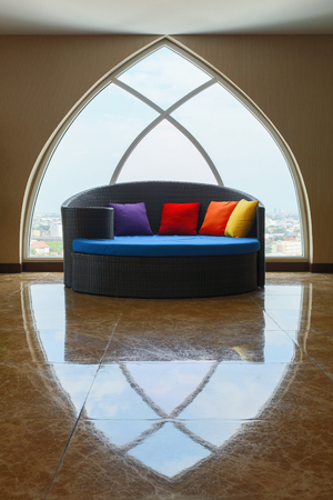 Huge blue round sofa bed with colorful pillows in front of dome skylight windows.の写真素材