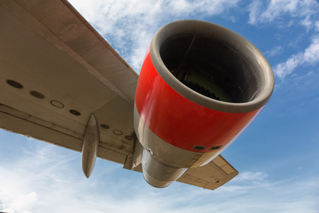Aircraft jet engine beneath large wing with clear blue sky.の写真素材