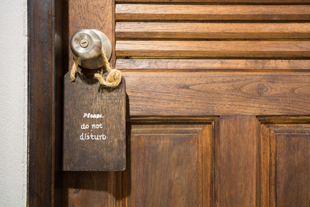 do not disturb sign on a wooden plate hang on a wooden door.の写真素材