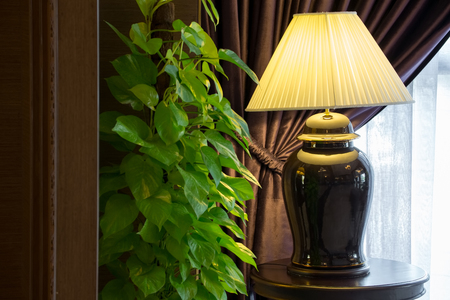 Black ceramic lamp decorated in a living room with dark brown and white sparse curtains.の写真素材