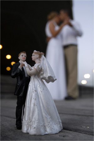 Bride and groom dolls in front of a real live bride and groom. (in the background, out of focus)の写真素材