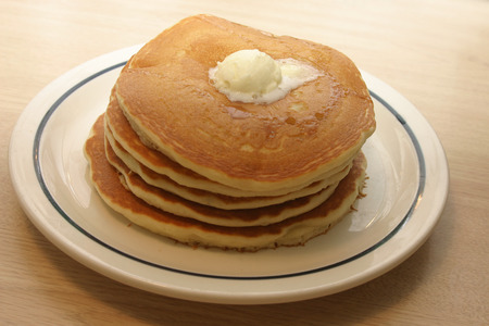 A stack of five pancakes, butter on top