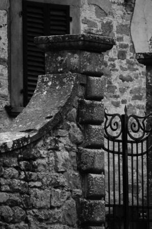 Stone fence and wrought iron gate, typical glimpse of a village in Tuscanyの写真素材