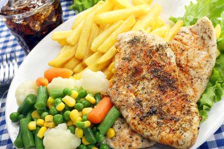Chicken grilled fillet in herbs with fresh vegetable and friesの写真素材