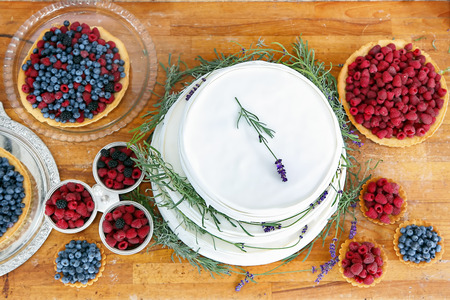 Wedding cake on wooden background with blueberries raspberries and lavender decorationの写真素材