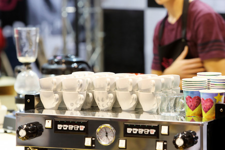 White cup of coffee at the coffee machine and baristaの写真素材