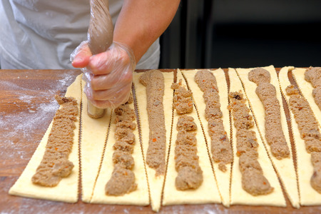 Baker adds pie filling for croissantsの写真素材